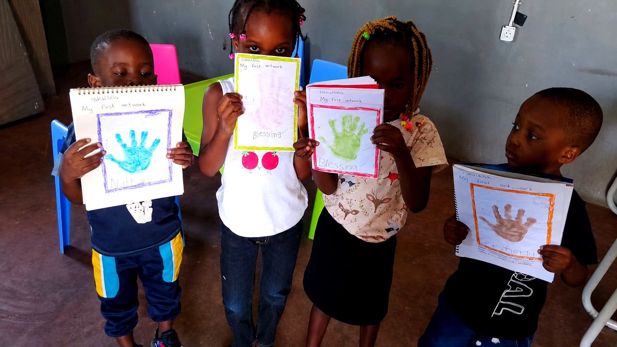 Young students proudly holding up their first artwork