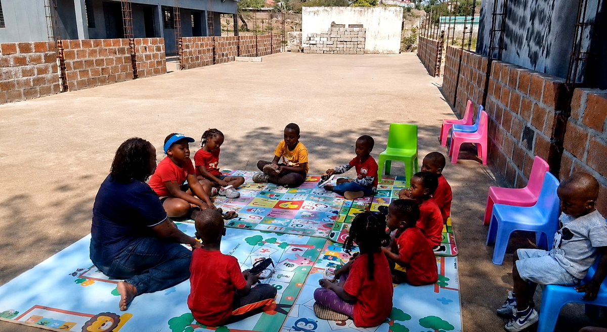 Students in an outdoor lesson on alphabet mats with their teacher